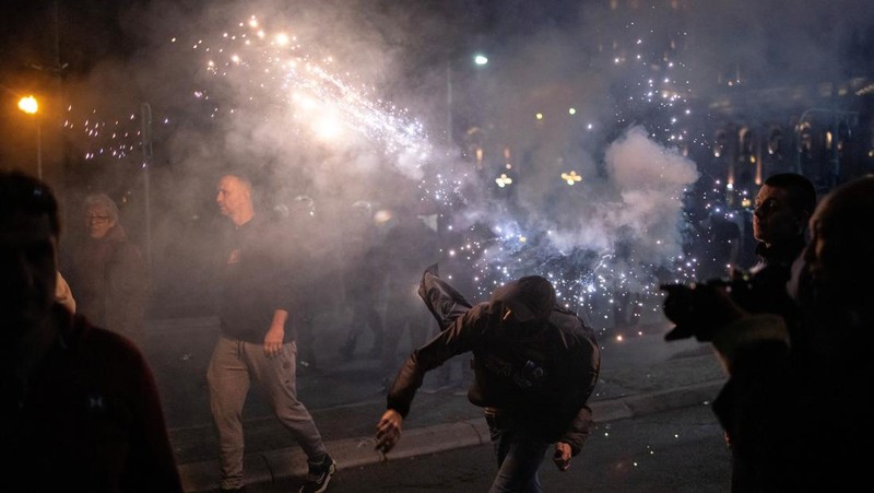 Seorang demonstran antipemerintah memberi isyarat di depan petugas penegak hukum dengan perlengkapan anti huru hara di dekat parlemen di Beograd, Serbia, 2 November 2025. (REUTERS/Marko Djurica)