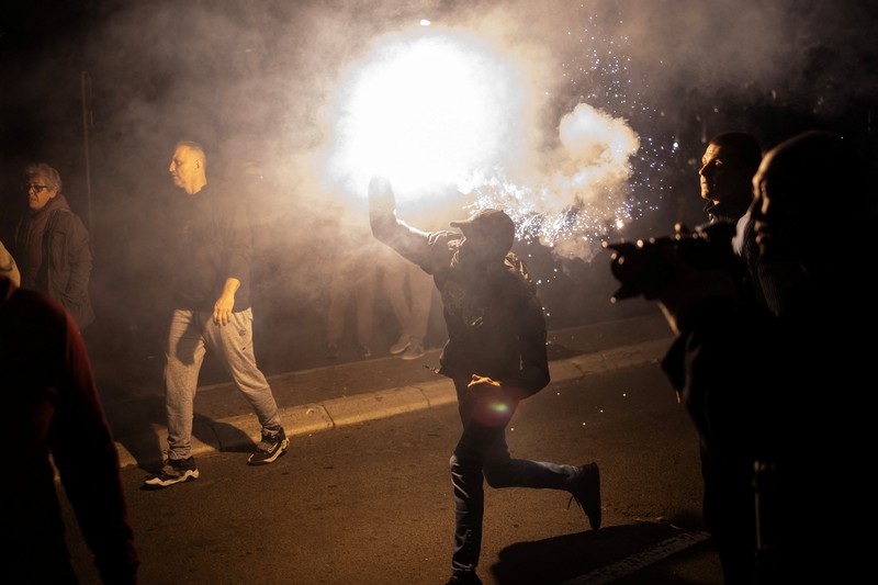 Seorang demonstran antipemerintah memberi isyarat di depan petugas penegak hukum dengan perlengkapan anti huru hara di dekat parlemen di Beograd, Serbia, 2 November 2025. (REUTERS/Marko Djurica)