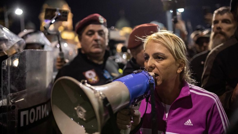 Seorang demonstran antipemerintah memberi isyarat di depan petugas penegak hukum dengan perlengkapan anti huru hara di dekat parlemen di Beograd, Serbia, 2 November 2025. (REUTERS/Marko Djurica)