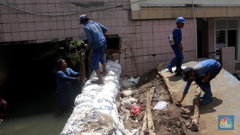 Petugas Dinas SDA menata karung pasir untuk penurapan sementara tanggul Baswedan yang jebol di Jati Padang, Pasar Minggu, Jakarta Selatan, Selasa (4/11/2025). (CNBC Indonesia/Muhammad Sabki)