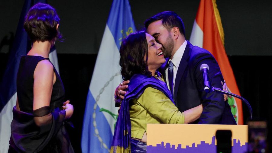Calon walikota New York City dari Partai Demokrat, Zohran Mamdani, mencium ibunya, Mira Nair, sementara istrinya, Rama Duwaji, berdiri di samping mereka, setelah memenangi pemilihan Wali Kota New York City 2025, pada rapat umum malam pemilihan di wilayah Brooklyn, New York City, New York, AS, 4 November 2025. (REUTERS/Jeenah Moon)