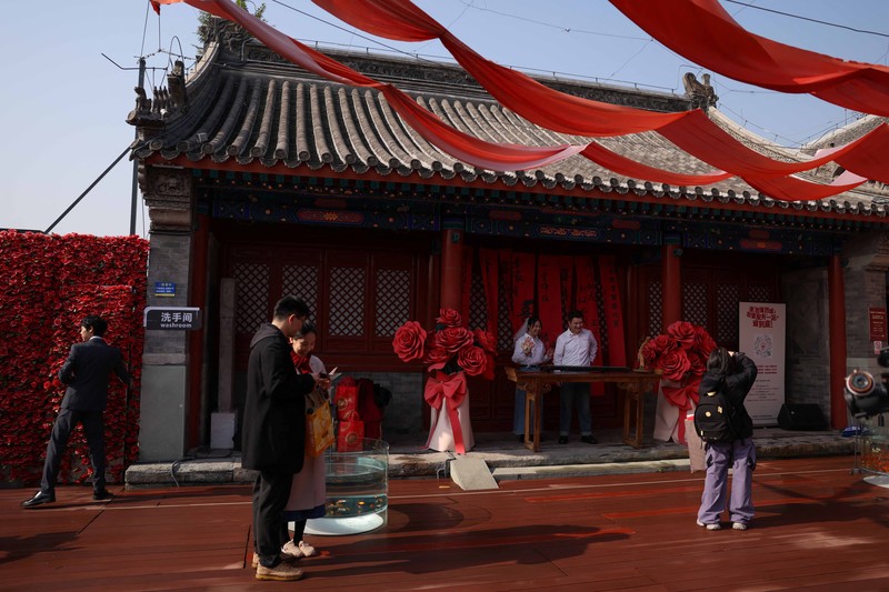 Wang Jieyu, 31, dan Zhan Yongqiang, 33, berpose untuk seorang fotografer dengan surat nikah mereka setelah mereka mendaftar di Kuil Huguo Guanyin, di Beijing, Tiongkok, 28 Oktober 2025. (REUTERS/Tingshu Wang)