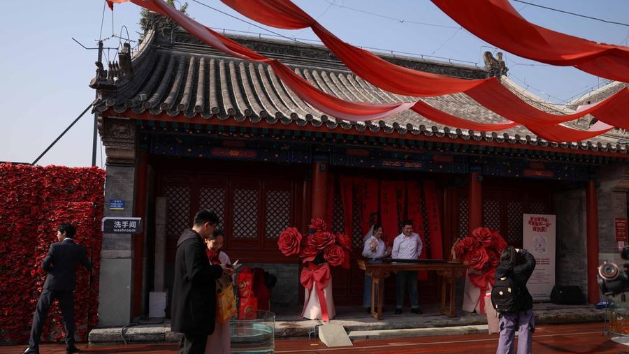 Wang Jieyu, 31, dan Zhan Yongqiang, 33, berpose untuk seorang fotografer dengan surat nikah mereka setelah mereka mendaftar di Kuil Huguo Guanyin, di Beijing, Tiongkok, 28 Oktober 2025. (REUTERS/Tingshu Wang)