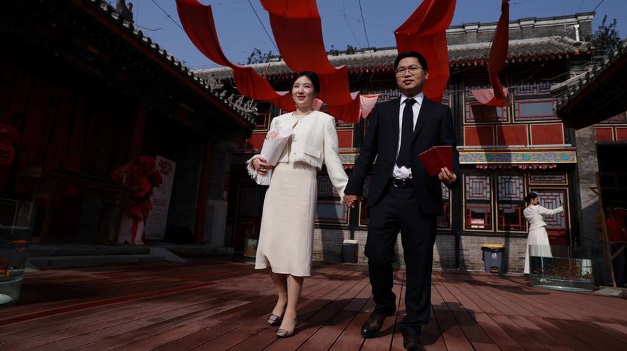 Wang Jieyu, 31, dan Zhan Yongqiang, 33, berpose untuk seorang fotografer dengan surat nikah mereka setelah mereka mendaftar di Kuil Huguo Guanyin, di Beijing, Tiongkok, 28 Oktober 2025. (REUTERS/Tingshu Wang)