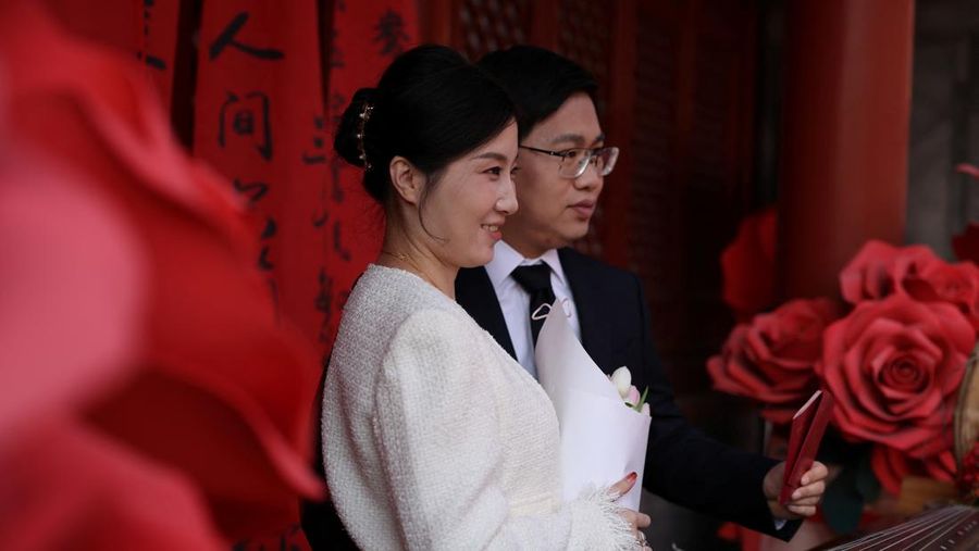 Wang Jieyu, 31, dan Zhan Yongqiang, 33, berpose untuk seorang fotografer dengan surat nikah mereka setelah mereka mendaftar di Kuil Huguo Guanyin, di Beijing, Tiongkok, 28 Oktober 2025. (REUTERS/Tingshu Wang)