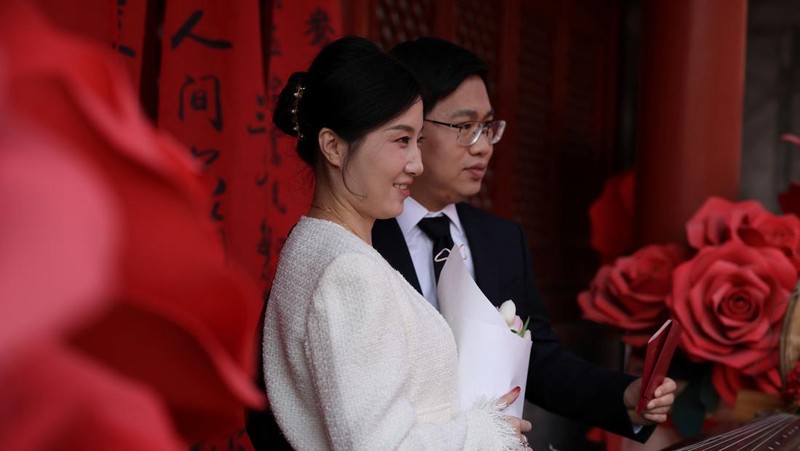 Wang Jieyu, 31, dan Zhan Yongqiang, 33, berpose untuk seorang fotografer dengan surat nikah mereka setelah mereka mendaftar di Kuil Huguo Guanyin, di Beijing, Tiongkok, 28 Oktober 2025. (REUTERS/Tingshu Wang)