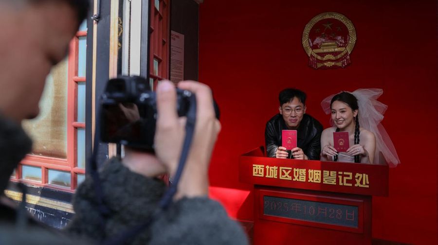 Wang Jieyu, 31, dan Zhan Yongqiang, 33, berpose untuk seorang fotografer dengan surat nikah mereka setelah mereka mendaftar di Kuil Huguo Guanyin, di Beijing, Tiongkok, 28 Oktober 2025. (REUTERS/Tingshu Wang)
