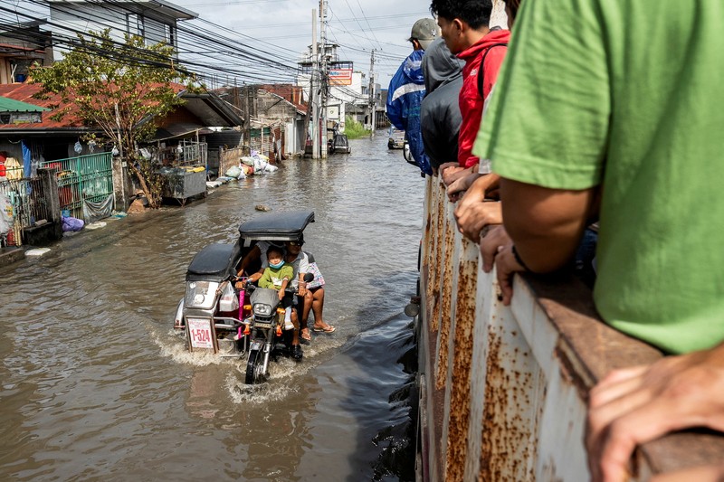 Seorang wanita berjalan melalui gang yang banjir setelah Topan Fung-wong melanda Kota Dagupan, Pangasinan, Filipina, 10 November 2025. (REUTERS/Noel Celis)