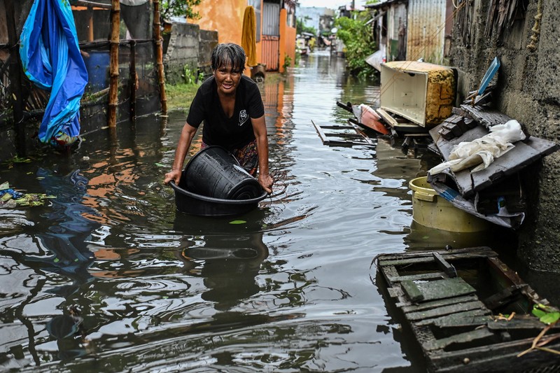 Seorang wanita berjalan melalui gang yang banjir setelah Topan Fung-wong melanda Kota Dagupan, Pangasinan, Filipina, 10 November 2025. (REUTERS/Noel Celis)