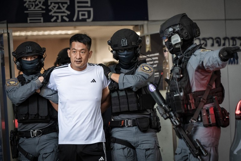 Raja judi asal China, She Zhijiang dikawal oleh Kepolisian Kerajaan Thailand keluar dari Kantor Polisi Bandara Suvarnabhumi di Bangkok, Thailand, Rabu (12/11/2025). (REUTERS/Thanaphon Wuttison)