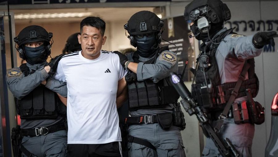 Raja judi asal China, She Zhijiang dikawal oleh Kepolisian Kerajaan Thailand keluar dari Kantor Polisi Bandara Suvarnabhumi di Bangkok, Thailand, Rabu (12/11/2025). (REUTERS/Thanaphon Wuttison)