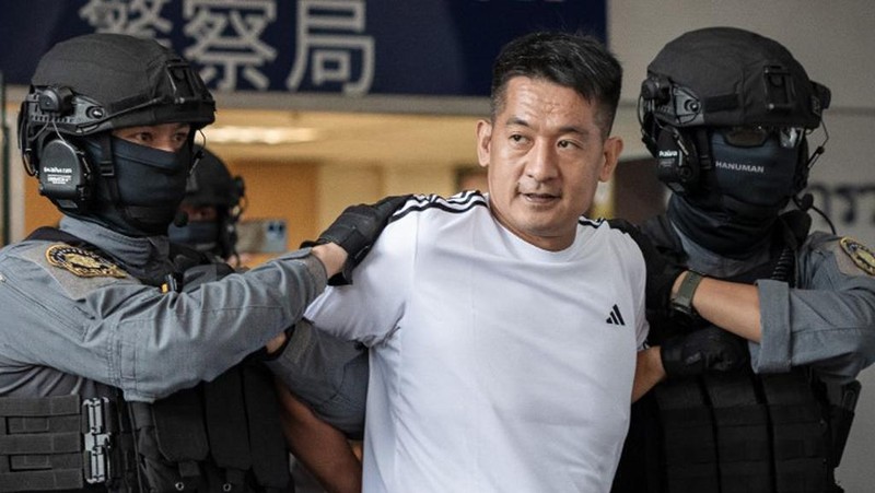 Raja judi asal China, She Zhijiang dikawal oleh Kepolisian Kerajaan Thailand keluar dari Kantor Polisi Bandara Suvarnabhumi di Bangkok, Thailand, Rabu (12/11/2025). (REUTERS/Thanaphon Wuttison)