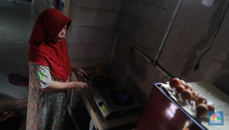 Warga memasak menggunakan kompor biogas melalui instalasi tangki septik komunal di permukiman Gang Delta, Pekayon, Pasar Rebo, Jakarta Timur, Kamis (13/11/2025). (CNBC Indonesia/Muhamad Sabki)