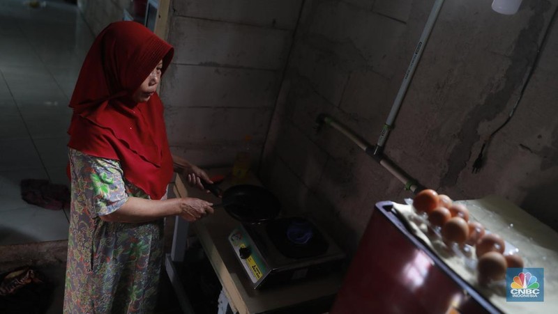 Warga memasak menggunakan kompor biogas melalui instalasi tangki septik komunal di permukiman Gang Delta, Pekayon, Pasar Rebo, Jakarta Timur, Kamis (13/11/2025). (CNBC Indonesia/Muhamad Sabki)