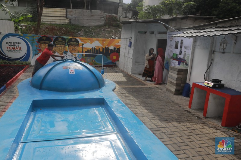 Warga memasak menggunakan kompor biogas melalui instalasi tangki septik komunal di permukiman Gang Delta, Pekayon, Pasar Rebo, Jakarta Timur, Kamis (13/11/2025). (CNBC Indonesia/Muhamad Sabki)
