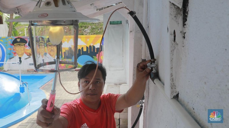 Warga memasak menggunakan kompor biogas melalui instalasi tangki septik komunal di permukiman Gang Delta, Pekayon, Pasar Rebo, Jakarta Timur, Kamis (13/11/2025). (CNBC Indonesia/Muhamad Sabki)