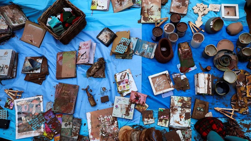 Orang-orang membawa sapu dan sekop berjalan di jalan, setelah banjir parah yang disebabkan oleh Badai Claudia, di Monmouth, Wales, Inggris, 16 November 2025. (REUTERS/Isabel Infantes)