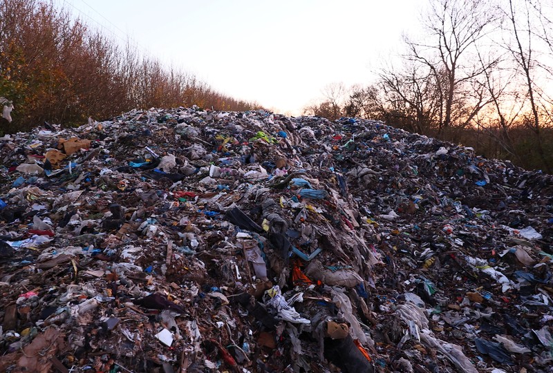 Seorang pria berjalan melewati tumpukan sampah yang dibuang secara ilegal di dataran banjir di sebelah jalan A34, yang memicu penyelidikan Badan Lingkungan Hidup terhadap dugaan kejahatan terorganisir, dekat Kidlington, Oxfordshire, Inggris, 17 November 2025. (REUTERS/Isabel Infantes)