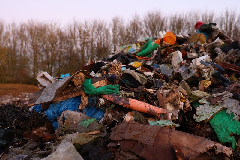 Seorang pria berjalan melewati tumpukan sampah yang dibuang secara ilegal di dataran banjir di sebelah jalan A34, yang memicu penyelidikan Badan Lingkungan Hidup terhadap dugaan kejahatan terorganisir, dekat Kidlington, Oxfordshire, Inggris, 17 November 2025. (REUTERS/Isabel Infantes)