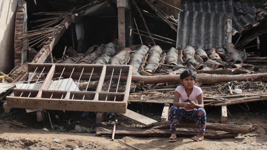 Seorang anak duduk di luar rumah yang rusak akibat tanah longsor setelah enam jam hujan deras yang menghancurkan rumah-rumah dan menyebabkan orang hilang, di Achira, Santa Cruz, Bolivia, 18 November 2025. (REUTERS/Ipa Ibanez)