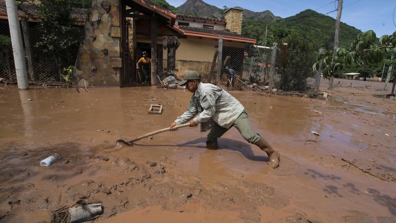 Seorang anak duduk di luar rumah yang rusak akibat tanah longsor setelah enam jam hujan deras yang menghancurkan rumah-rumah dan menyebabkan orang hilang, di Achira, Santa Cruz, Bolivia, 18 November 2025. (REUTERS/Ipa Ibanez)