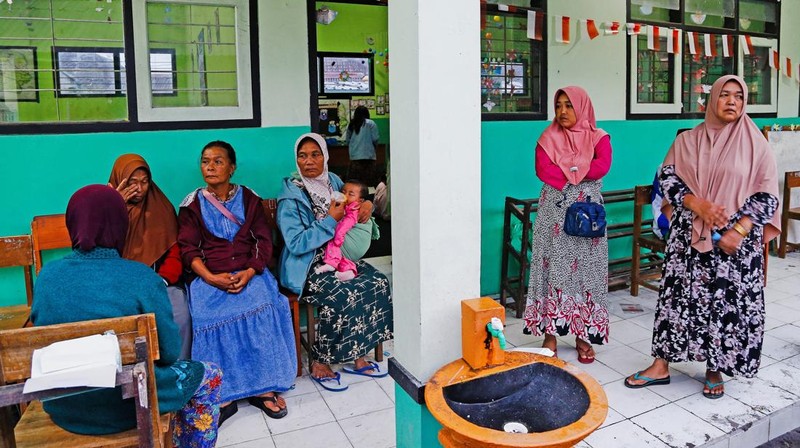 Warga setempat mengendarai sepeda motor saat Gunung Semeru memuntahkan abu vulkanik saat erupsi seperti terlihat di latar belakang, di Desa Supiturang, Lumajang, Provinsi Jawa Timur, Indonesia, 20 November 2025. REUTERS/Dipta Wahyu
