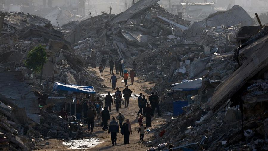 Warga Palestina berjalan di antara tumpukan puing, di tengah gencatan senjata antara Israel dan Hamas, di Jalur Gaza utara, 19 November 2025. REUTERS/Mahmoud Issa