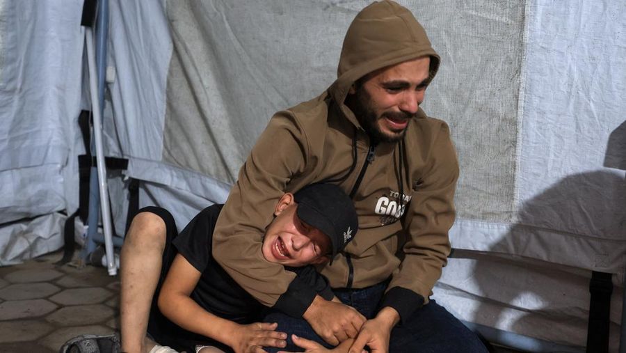 Seorang pria dan seorang anak berduka di dekat jenazah seorang warga Palestina yang tewas dalam serangan udara Israel, menurut petugas medis, di Rumah Sakit Al-Ahli Arab di Kota Gaza, 19 November 2025. REUTERS/Dawoud Abu Alkas
