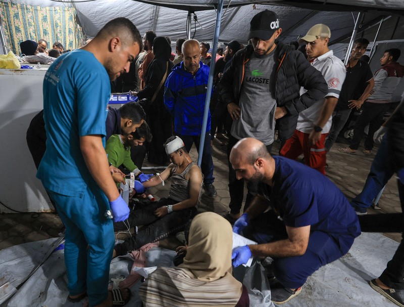 Seorang pria dan seorang anak berduka di dekat jenazah seorang warga Palestina yang tewas dalam serangan udara Israel, menurut petugas medis, di Rumah Sakit Al-Ahli Arab di Kota Gaza, 19 November 2025. REUTERS/Dawoud Abu Alkas