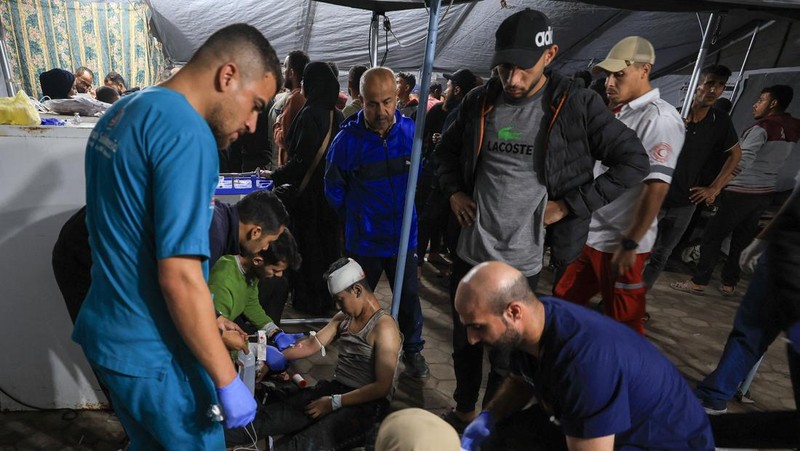 Seorang pria dan seorang anak berduka di dekat jenazah seorang warga Palestina yang tewas dalam serangan udara Israel, menurut petugas medis, di Rumah Sakit Al-Ahli Arab di Kota Gaza, 19 November 2025. REUTERS/Dawoud Abu Alkas