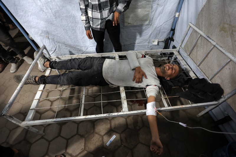 Seorang pria dan seorang anak berduka di dekat jenazah seorang warga Palestina yang tewas dalam serangan udara Israel, menurut petugas medis, di Rumah Sakit Al-Ahli Arab di Kota Gaza, 19 November 2025. REUTERS/Dawoud Abu Alkas