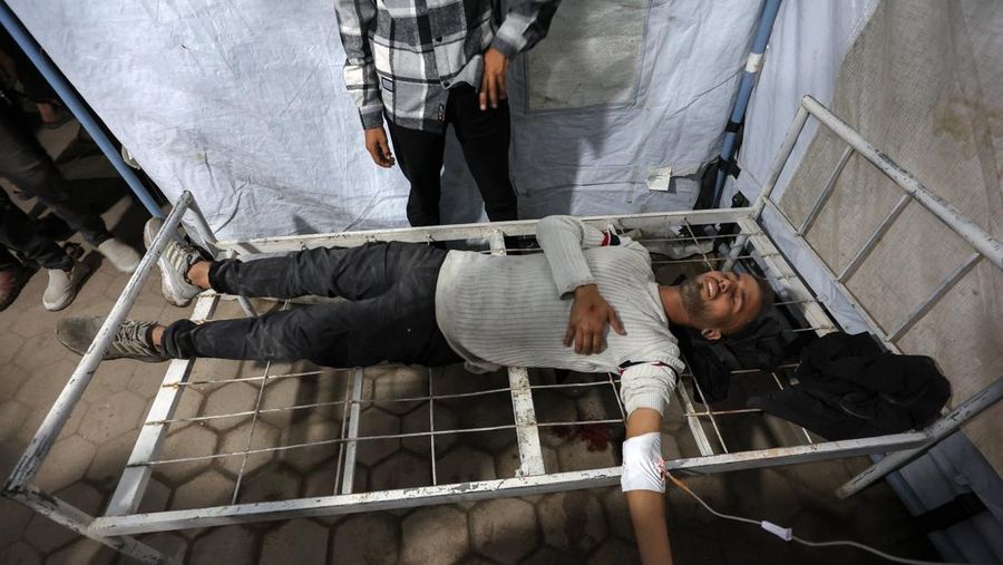 Seorang pria dan seorang anak berduka di dekat jenazah seorang warga Palestina yang tewas dalam serangan udara Israel, menurut petugas medis, di Rumah Sakit Al-Ahli Arab di Kota Gaza, 19 November 2025. REUTERS/Dawoud Abu Alkas