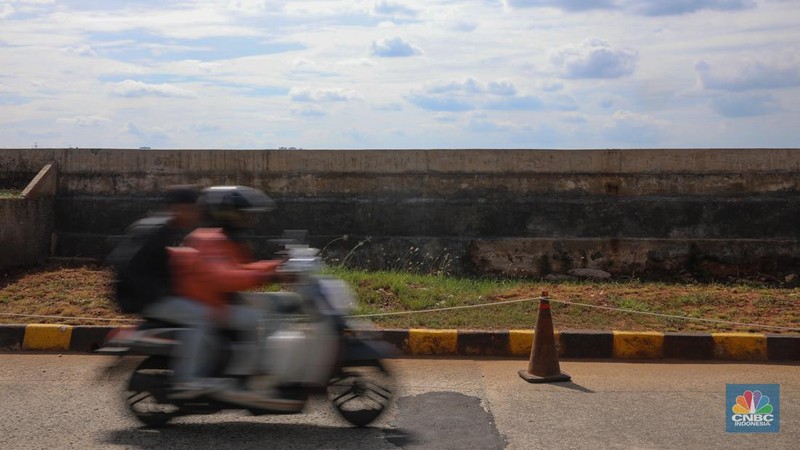 Pengendara sepeda motor melintas di samping tanggul Pantai Mutiara, Penjaringan, Jakarta Utara, Senin (24/11/2025). (CNBC Indonesia/Faisal Rahman)