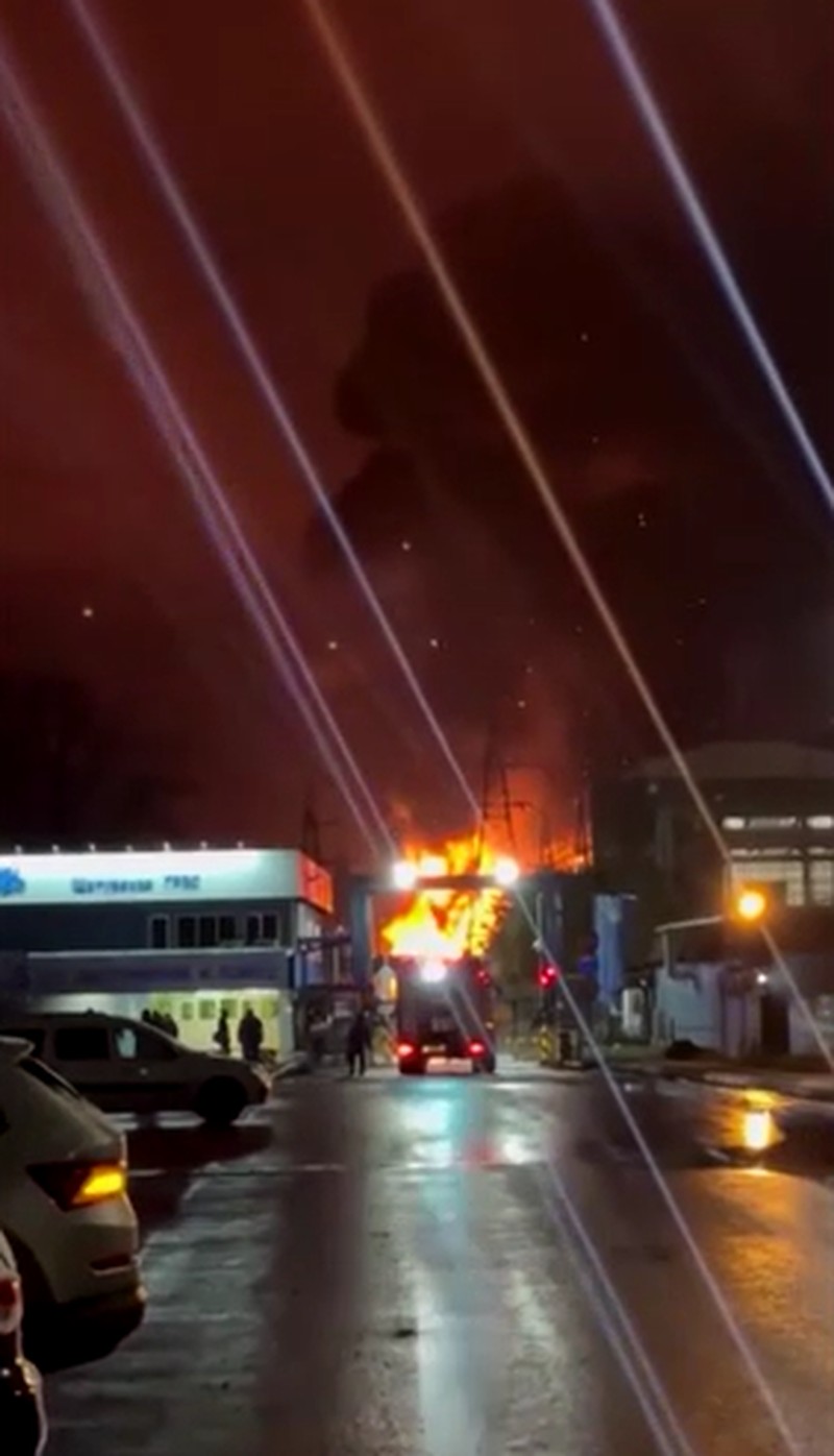 A person stands by an emergency vehicle as fire and smoke rise around the Shatura Power Station in Shatura, Russia, after Ukrainian drones struck the facility early Sunday, Moscow region governor Andrei Vorobyov said, in this still image taken from a social media video released November November 23, 2025. SOCIAL MEDIA/via REUTERS  THIS IMAGE HAS BEEN SUPPLIED BY A THIRD PARTY. NO RESALES. NO ARCHIVES. VERIFICATION LINES: - Reuters was able to confirm the location as buildings, signages and roadmap layout match with file images and satellite imagery. Date could not be independently verified. However, the governor of Moscow Region said on Telegram that Shatura Thermal Plant was attacked and caused fire this morning (November 23, 2025).