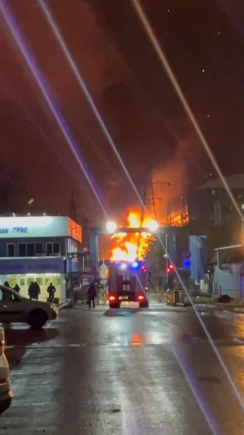 A person stands by an emergency vehicle as fire and smoke rise around the Shatura Power Station in Shatura, Russia, after Ukrainian drones struck the facility early Sunday, Moscow region governor Andrei Vorobyov said, in this still image taken from a social media video released November November 23, 2025. SOCIAL MEDIA/via REUTERS  THIS IMAGE HAS BEEN SUPPLIED BY A THIRD PARTY. NO RESALES. NO ARCHIVES. VERIFICATION LINES: - Reuters was able to confirm the location as buildings, signages and roadmap layout match with file images and satellite imagery. Date could not be independently verified. However, the governor of Moscow Region said on Telegram that Shatura Thermal Plant was attacked and caused fire this morning (November 23, 2025).