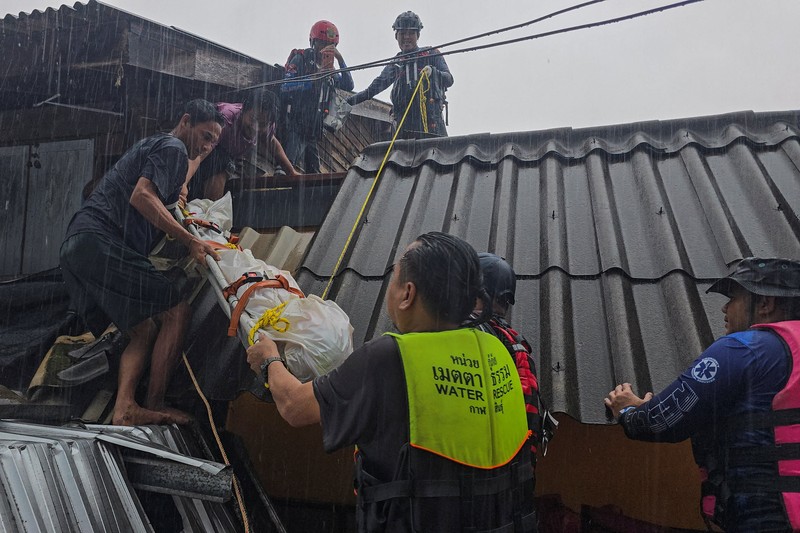 Seorang pria berpegangan pada tiang rambu jalan di jalan yang banjir setelah tersapu ke sana saat pergi keluar untuk mendapatkan persediaan makanan di distrik Hat Yai, yang terdampak hujan lebat yang melanda 10 provinsi di Thailand selatan dan menewaskan beberapa orang, di provinsi Songkhla, Thailand, 24 November 2025. (REUTERS/Sithichai Chootochana)