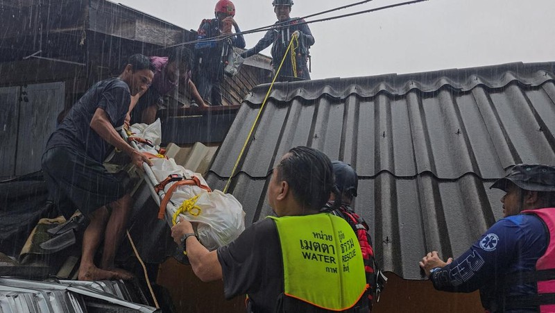 Seorang pria berpegangan pada tiang rambu jalan di jalan yang banjir setelah tersapu ke sana saat pergi keluar untuk mendapatkan persediaan makanan di distrik Hat Yai, yang terdampak hujan lebat yang melanda 10 provinsi di Thailand selatan dan menewaskan beberapa orang, di provinsi Songkhla, Thailand, 24 November 2025. (REUTERS/Sithichai Chootochana)
