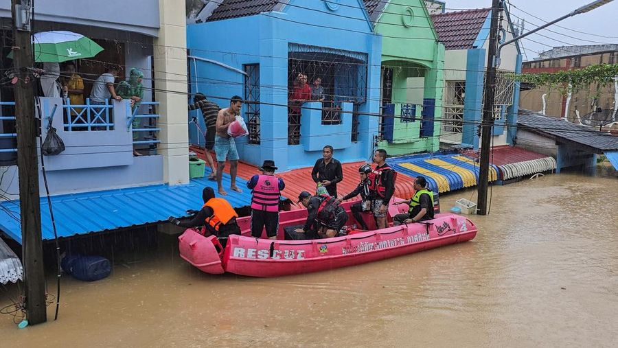 Seorang pria berpegangan pada tiang rambu jalan di jalan yang banjir setelah tersapu ke sana saat pergi keluar untuk mendapatkan persediaan makanan di distrik Hat Yai, yang terdampak hujan lebat yang melanda 10 provinsi di Thailand selatan dan menewaskan beberapa orang, di provinsi Songkhla, Thailand, 24 November 2025. (REUTERS/Sithichai Chootochana)
