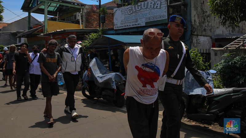 Petugas mengamankan terduga pelaku peredaean narkotika saat melakukan penggerebekan di kawasan Berland, Jalan Kesatrian, Matraman, Jakarta, Selasa (25/11/2025). (CNBC Indonesia/Faisal Rahman)