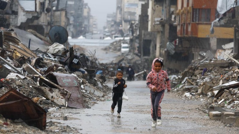 Warga Palestina yang mengungsi berkumpul di samping tenda-tenda di daerah yang banjir, pada hari hujan di Kota Gaza, 25 November 2025. (REUTERS/Mahmoud Issa)