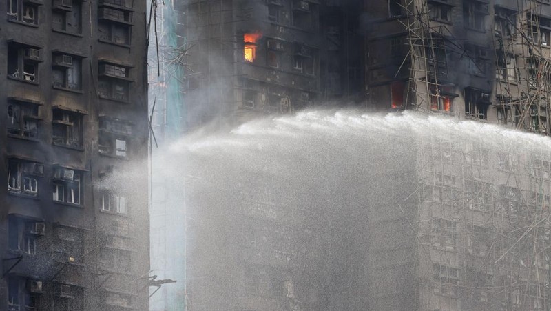 Polisi berjaga di lokasi kebakaran besar di perumahan Wang Fuk Court, di mana api melalap perancah bambu di beberapa blok, menewaskan sedikitnya 44 orang dan menyebabkan hampir 300 orang hilang, di Tai Po, Hong Kong, Tiongkok, 27 November 2025. (REUTERS/Tyrone Siu)