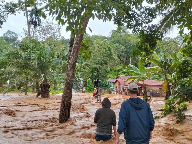 Seorang wanita berjalan bersama anaknya di daerah yang dilanda banjir bandang, menyusul hujan lebat di Malalak, Kabupaten Agam, provinsi Sumatera Barat, Indonesia, 27 November 2025. (REUTERS/Rafdi Rahmadi)