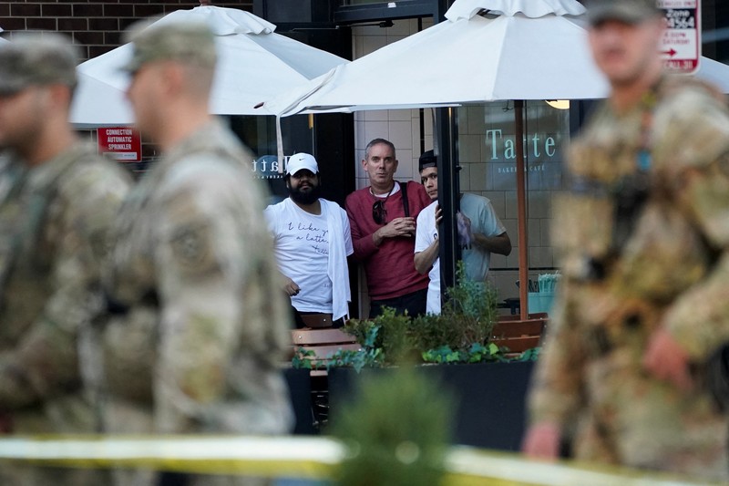 Anggota Garda Nasional berdiri di area yang ditutup dengan penanda bukti yang ditempatkan di tanah, setelah dua anggota Garda Nasional ditembak di dekat Gedung Putih di Washington, D.C., AS, 26 November 2025. (REUTERS/Nathan Howard)