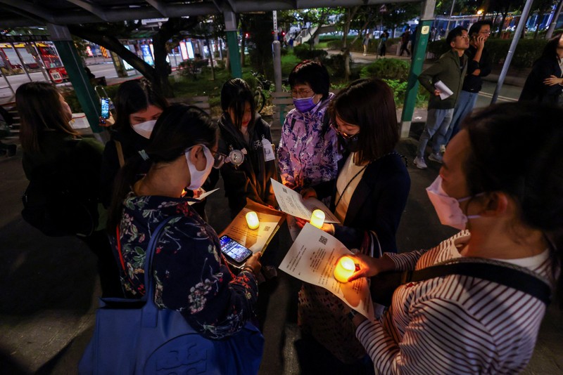 Orang-orang memegang kertas doa saat berkumpul, setelah kebakaran mematikan di kompleks perumahan Wang Fuk Court di Tai Po, Hong Kong, Cina, 28 November 2025. (REUTERS/Maxim Shemetov)