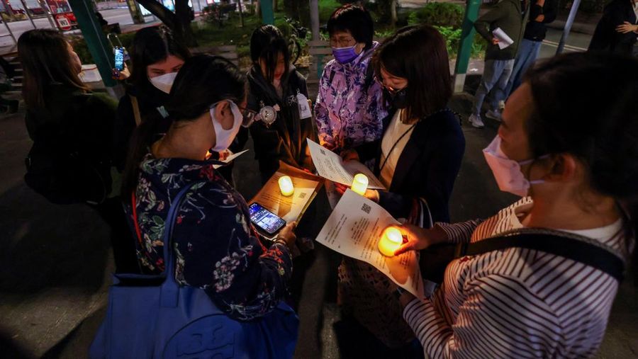 Orang-orang memegang kertas doa saat berkumpul, setelah kebakaran mematikan di kompleks perumahan Wang Fuk Court di Tai Po, Hong Kong, Cina, 28 November 2025. (REUTERS/Maxim Shemetov)