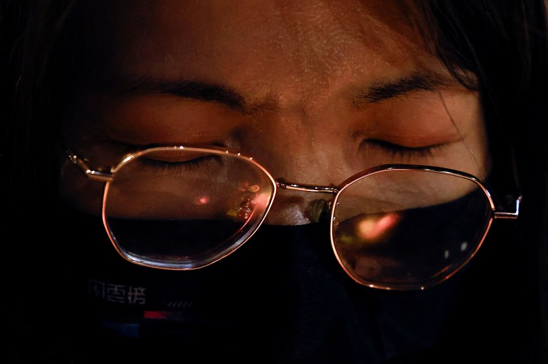 Orang-orang memegang kertas doa saat berkumpul, setelah kebakaran mematikan di kompleks perumahan Wang Fuk Court di Tai Po, Hong Kong, Cina, 28 November 2025. (REUTERS/Maxim Shemetov)