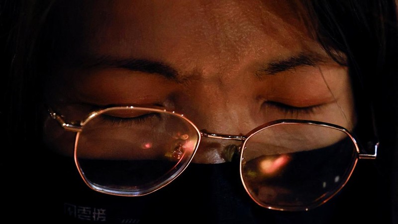 Orang-orang memegang kertas doa saat berkumpul, setelah kebakaran mematikan di kompleks perumahan Wang Fuk Court di Tai Po, Hong Kong, Cina, 28 November 2025. (REUTERS/Maxim Shemetov)