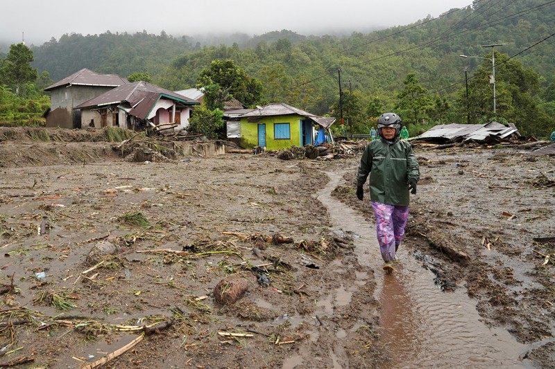 Seorang wanita berjalan bersama anaknya di daerah yang dilanda banjir bandang, menyusul hujan lebat di Malalak, Kabupaten Agam, provinsi Sumatera Barat, Indonesia, 27 November 2025. (REUTERS/Rafdi Rahmadi)