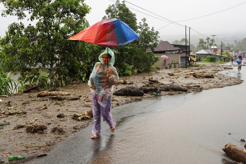 Seorang wanita berjalan bersama anaknya di daerah yang dilanda banjir bandang, menyusul hujan lebat di Malalak, Kabupaten Agam, provinsi Sumatera Barat, Indonesia, 27 November 2025. (REUTERS/Rafdi Rahmadi)