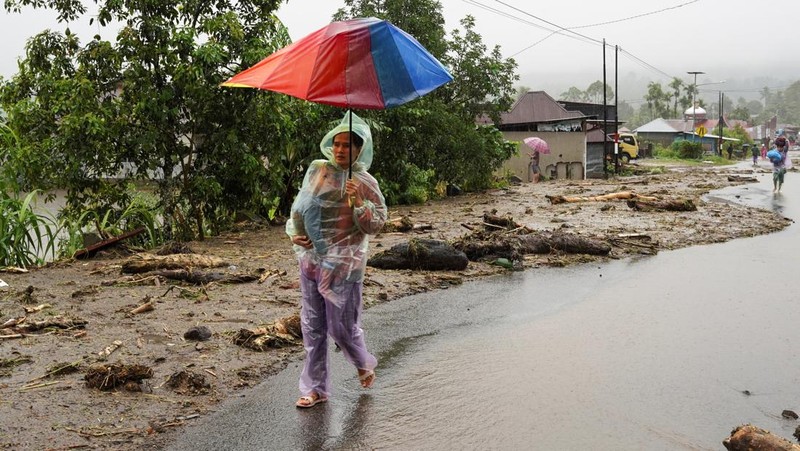 Seorang wanita berjalan bersama anaknya di daerah yang dilanda banjir bandang, menyusul hujan lebat di Malalak, Kabupaten Agam, provinsi Sumatera Barat, Indonesia, 27 November 2025. (REUTERS/Rafdi Rahmadi)